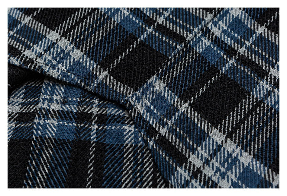Close-up of stitching and folded seams on blue, black, and gray plaid fabric.
