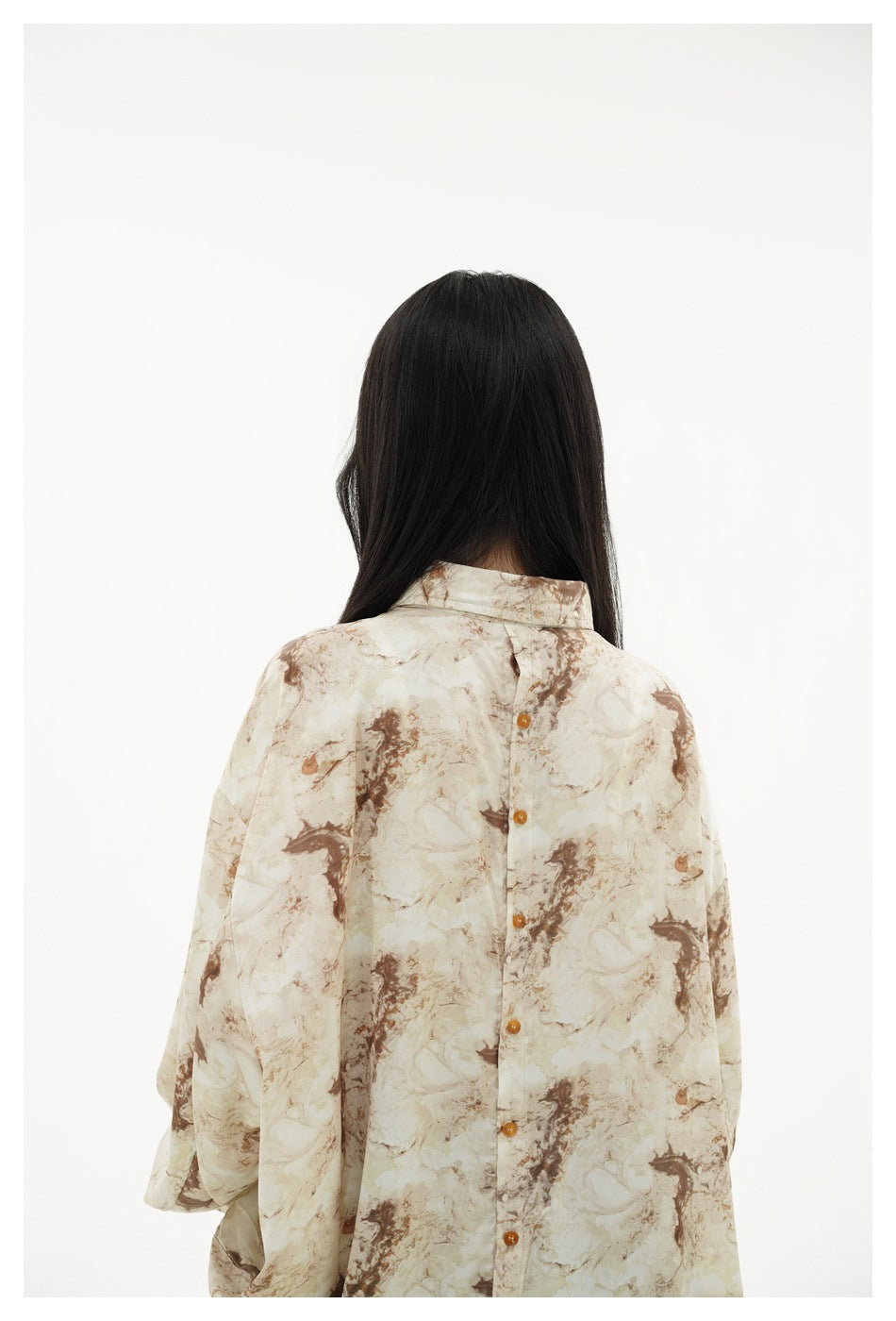 Close rear view of a model wearing the cream and brown marbled shirt, showing its back buttons.
