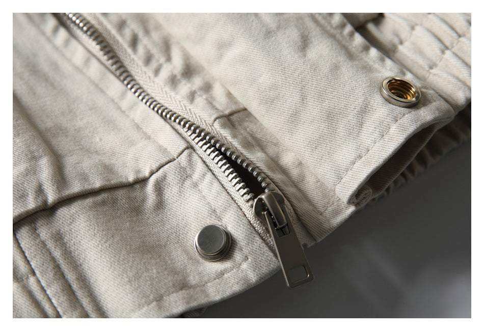 Close-up of a metal zipper and snap fasteners on a light beige jacket.