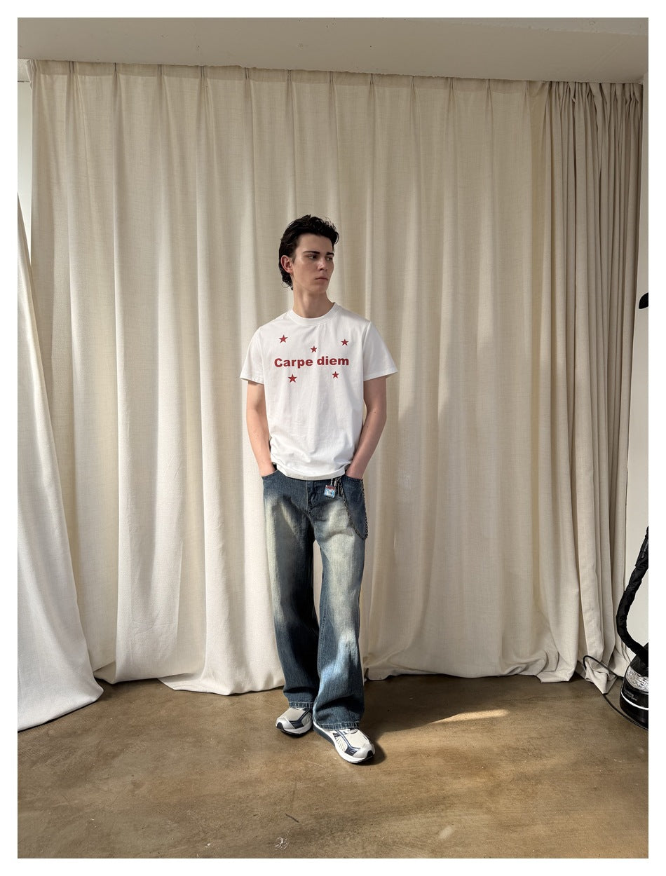 Full-length model wearing a white Carpe diem star-print T-shirt and loose faded jeans with a chain detail.