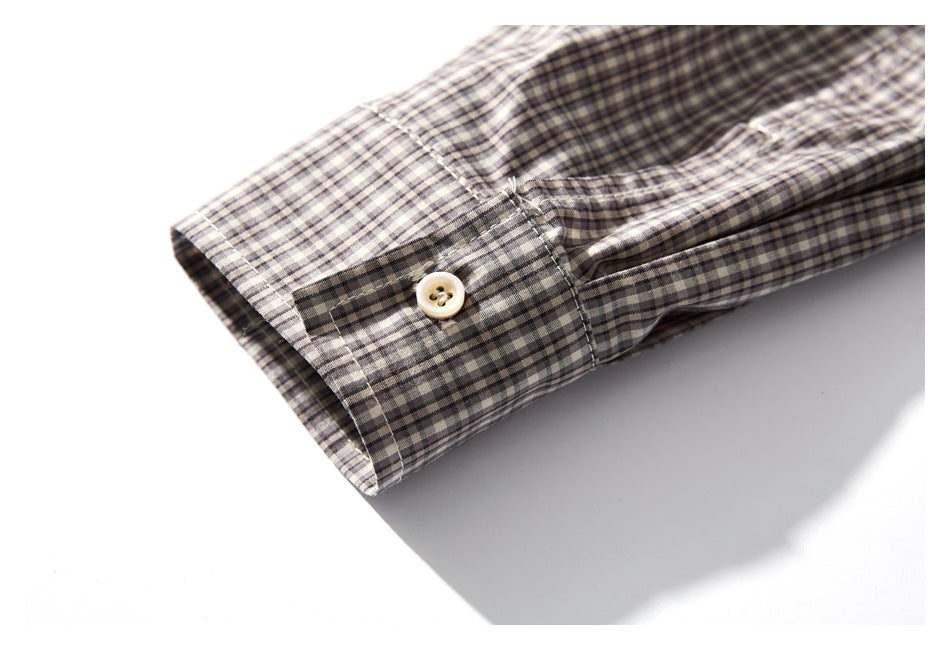 Close-up of a gray and cream checked shirt cuff with a light button and stitched buttonhole.