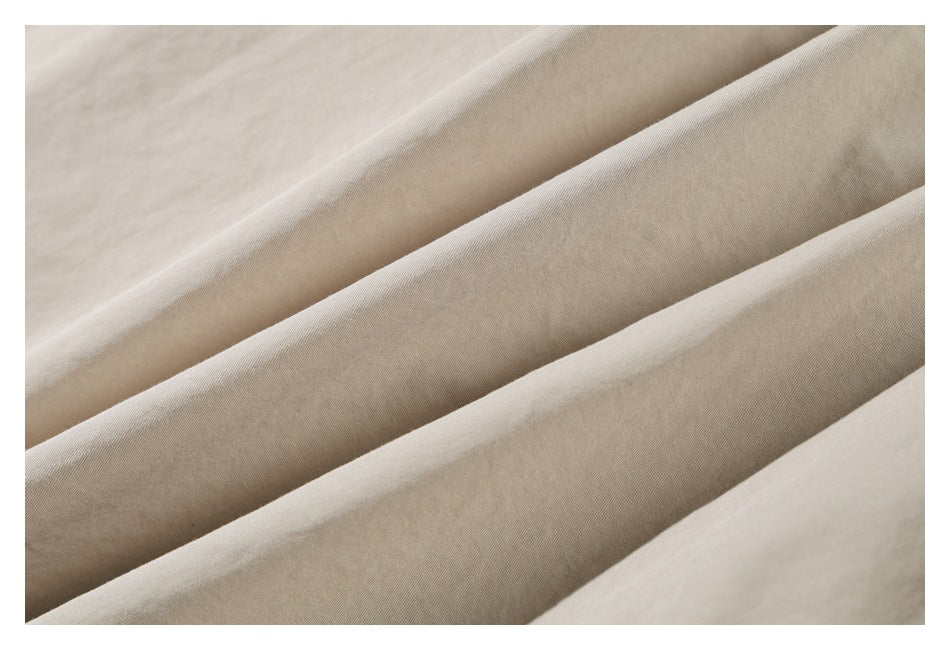 Close-up of the light khaki garment fabric arranged in soft folds.
