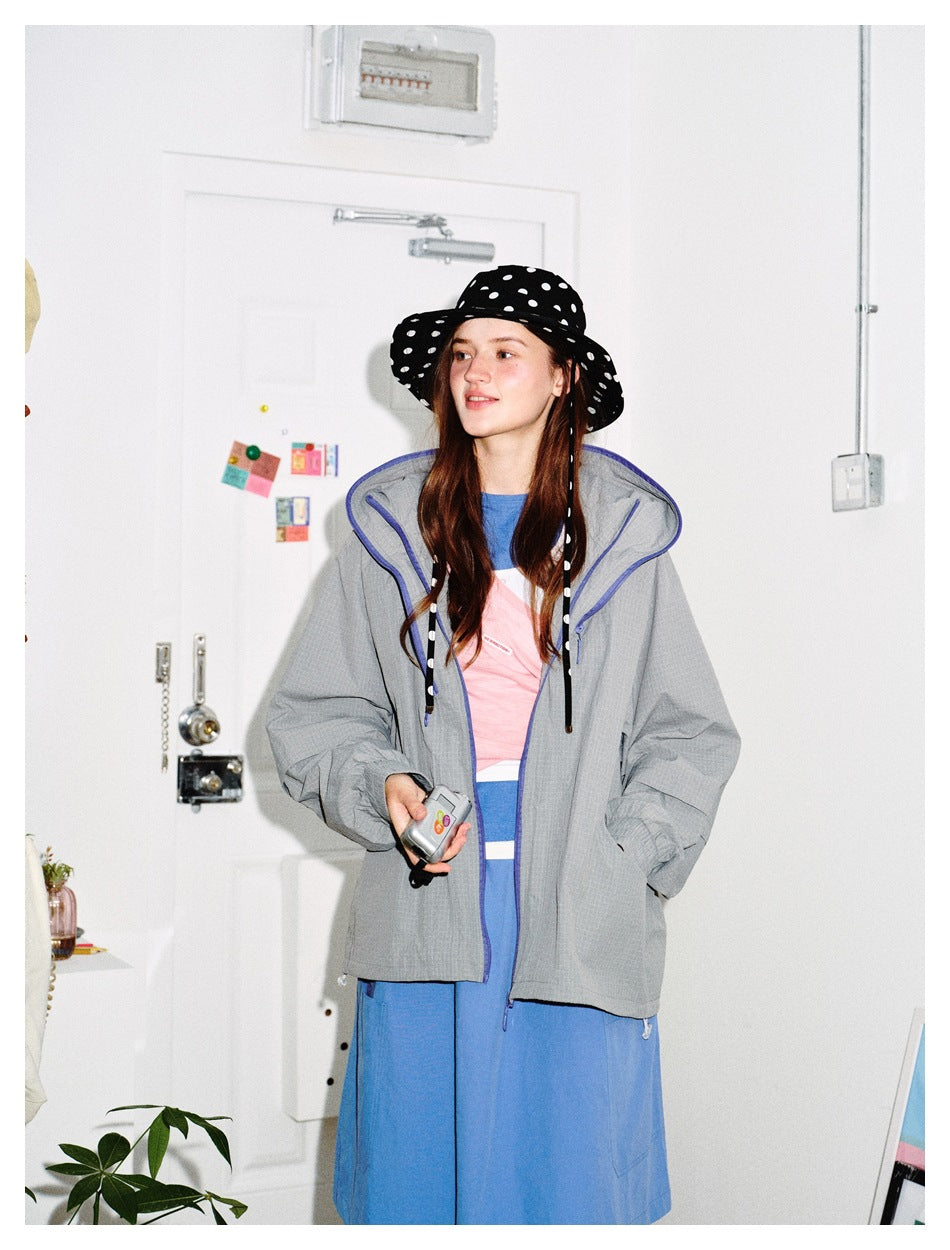 Front view of a model in a gray hooded jacket with blue zipper trim and colorful lining.