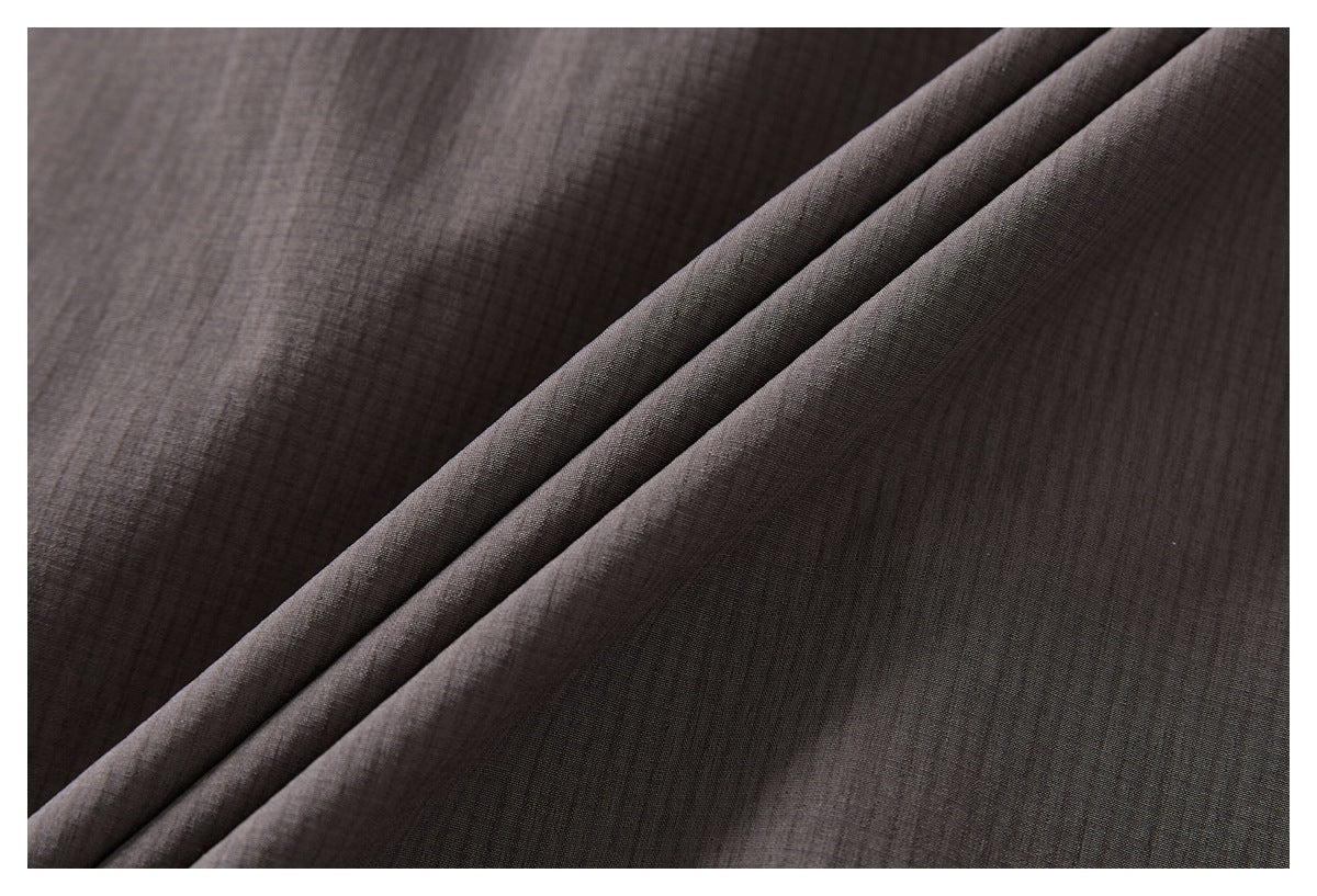 Close-up of dark charcoal-brown fabric draped in soft diagonal folds.