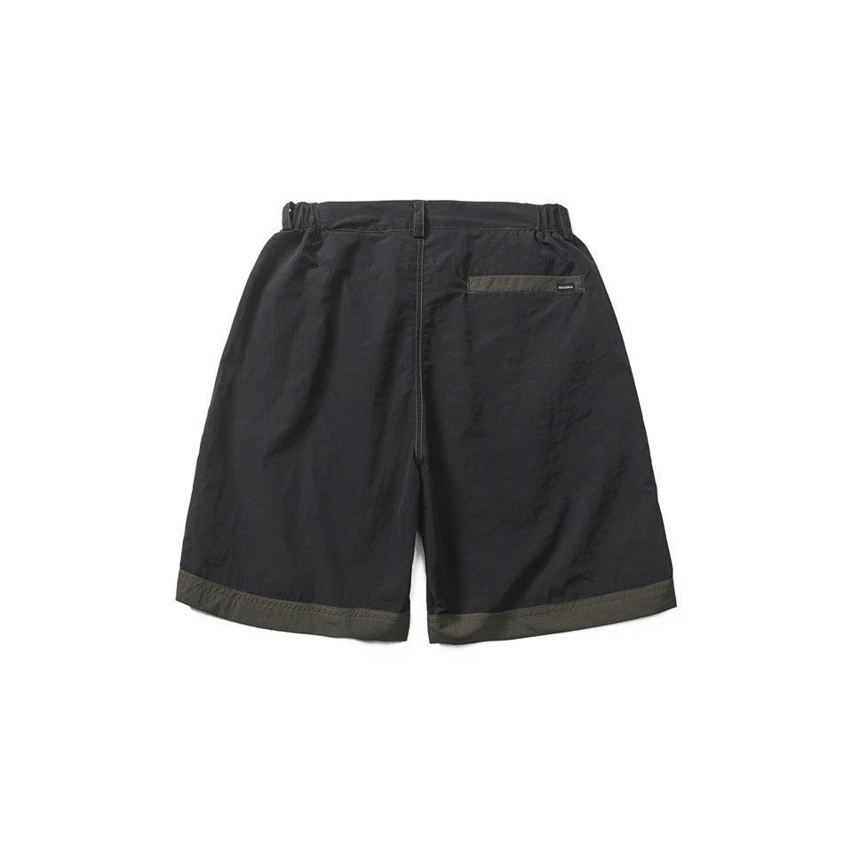 Back view of black shorts with olive hem band, elastic waistband and olive-trimmed back welt pocket