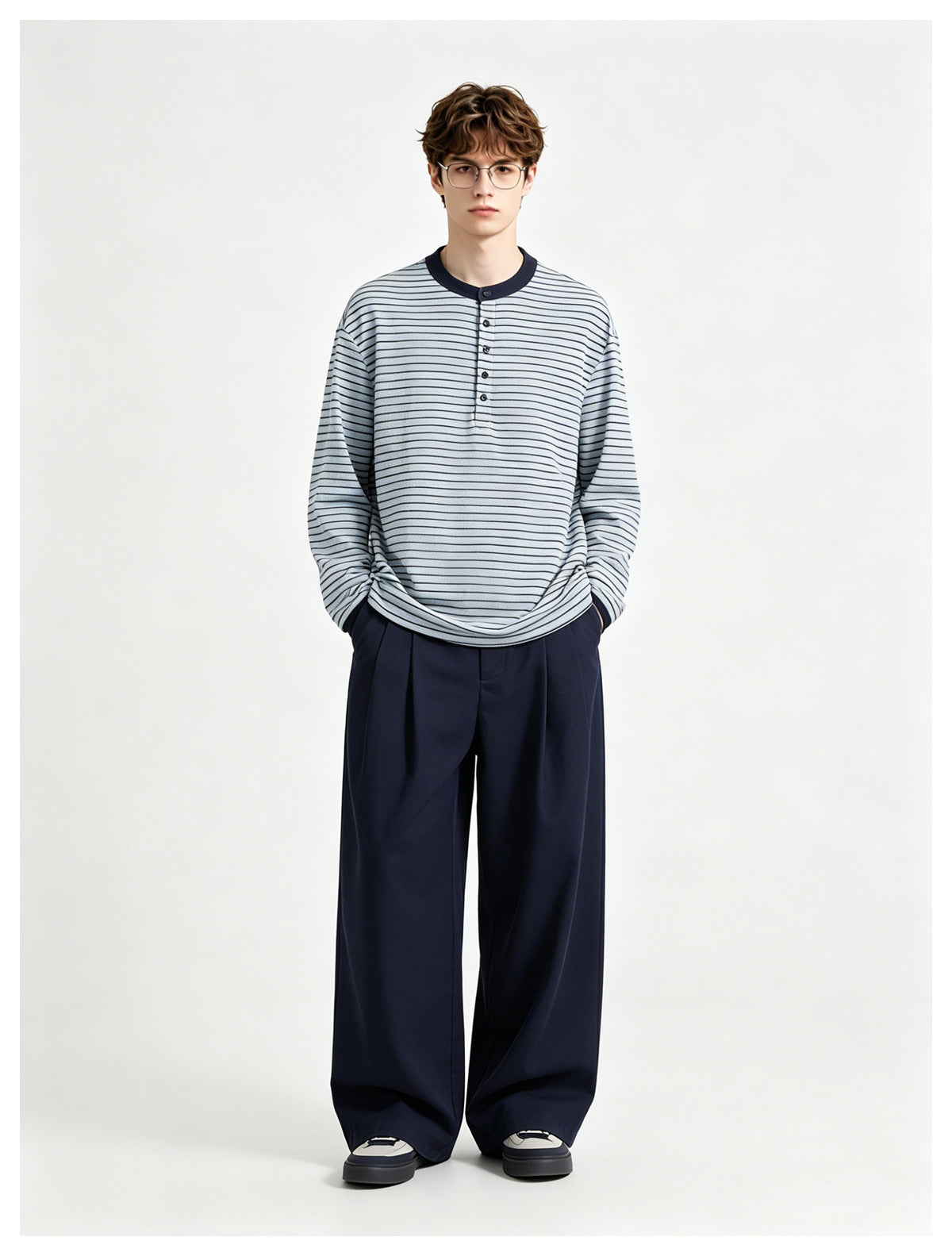 Model wearing a pale blue and navy striped long-sleeve henley with wide navy trousers.