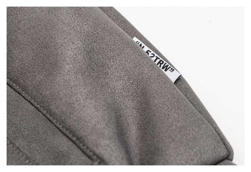 Close-up of charcoal gray fabric with a seam and a small white woven label bearing black lettering.