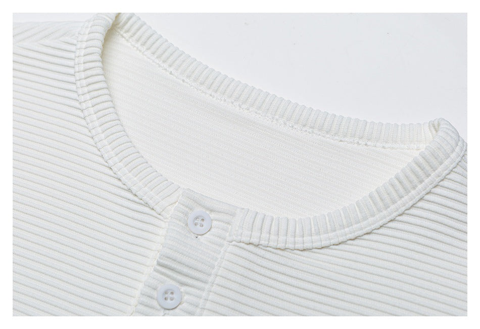 Close-up of a white ribbed henley shirt's round neckline and button placket.