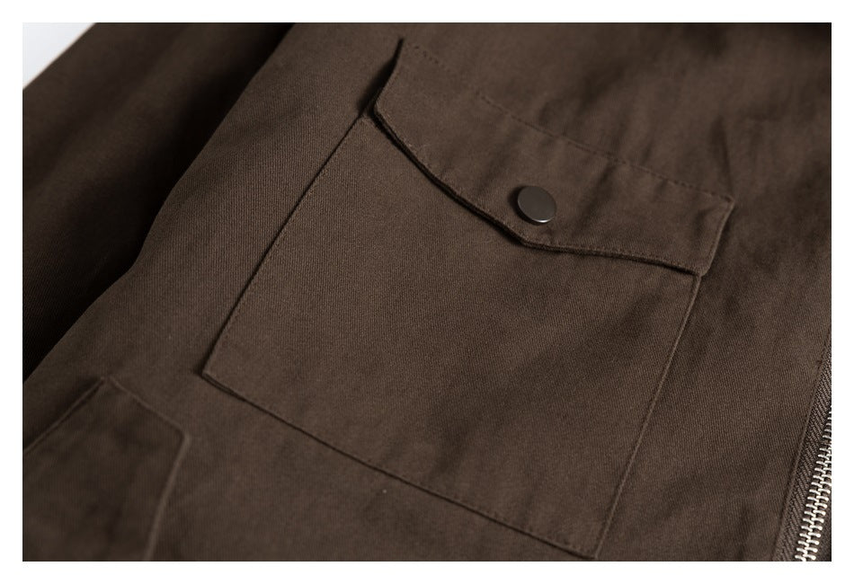 Close-up of a large brown jacket pocket with a snap-button flap and zipper alongside.