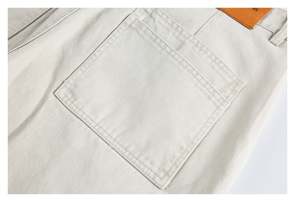 Close-up of a square back pocket and double stitching on light beige jeans.