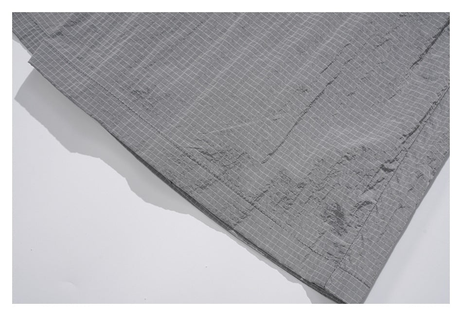 Close-up of gray grid-pattern trouser fabric, stitching, and a panel seam.