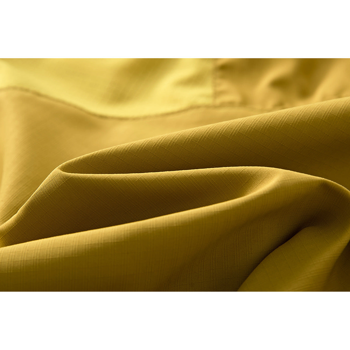 Close-up of mustard-yellow shorts fabric showing a fine grid texture and folds.