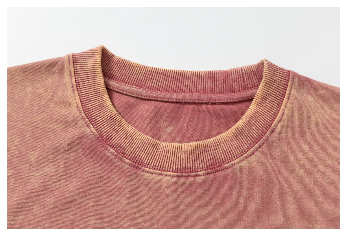 Close-up of a ribbed crew neckline on a pink, acid-washed T-shirt.