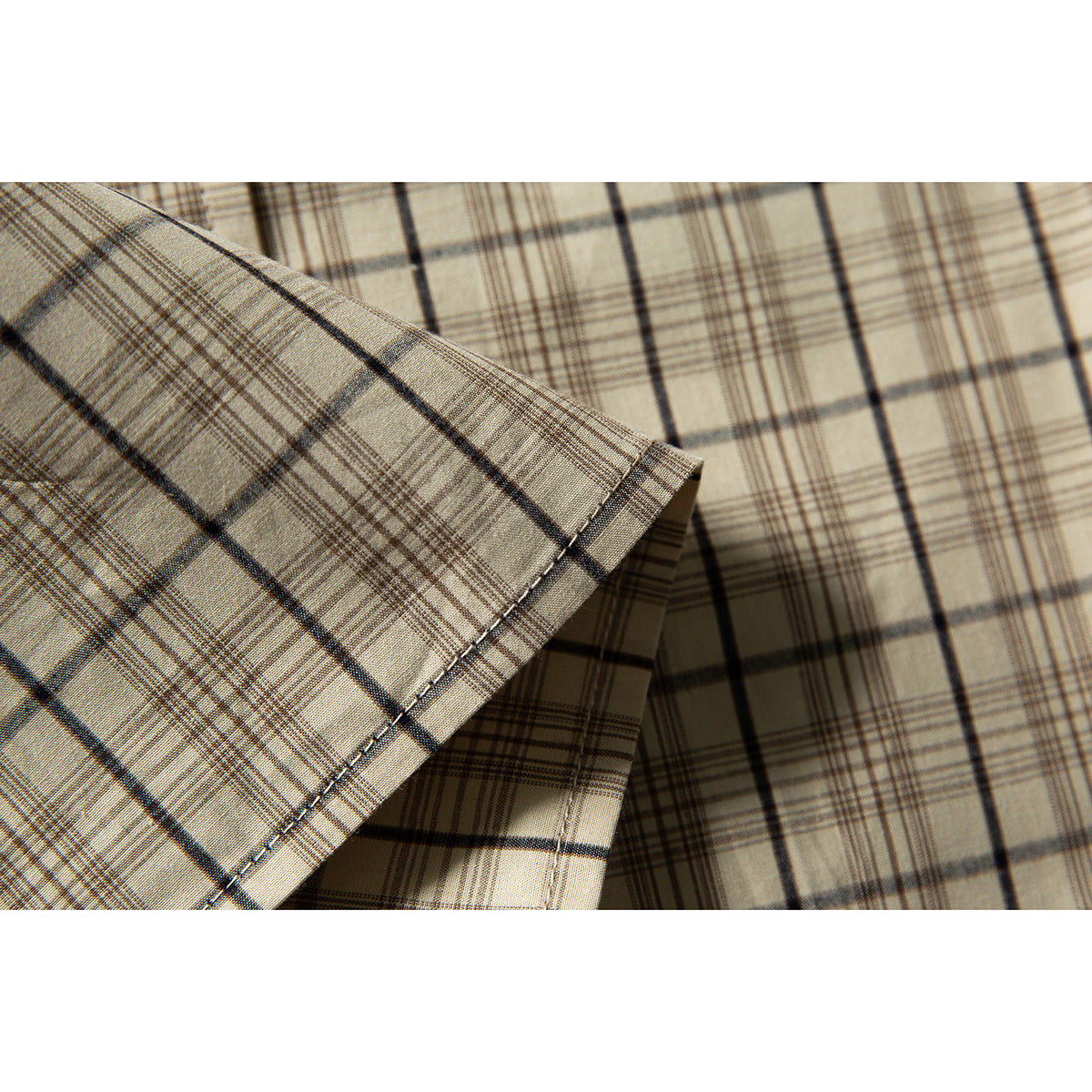 Close-up of beige plaid shirt fabric and a neatly stitched folded edge.