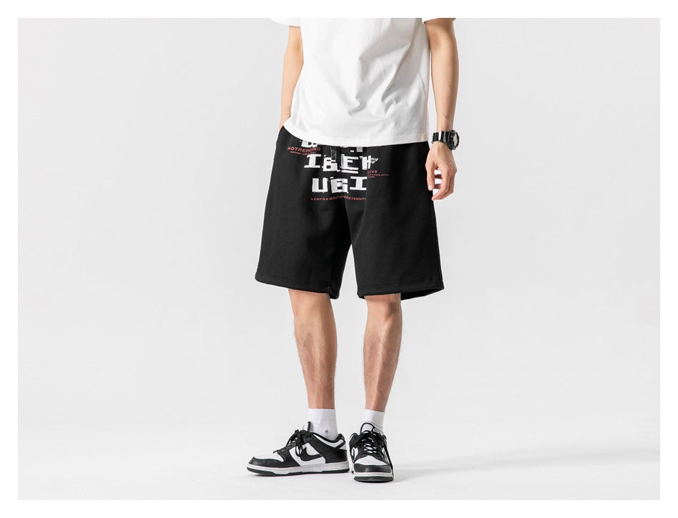 Front view of a model wearing black knee-length shorts with a large white and red graphic print.