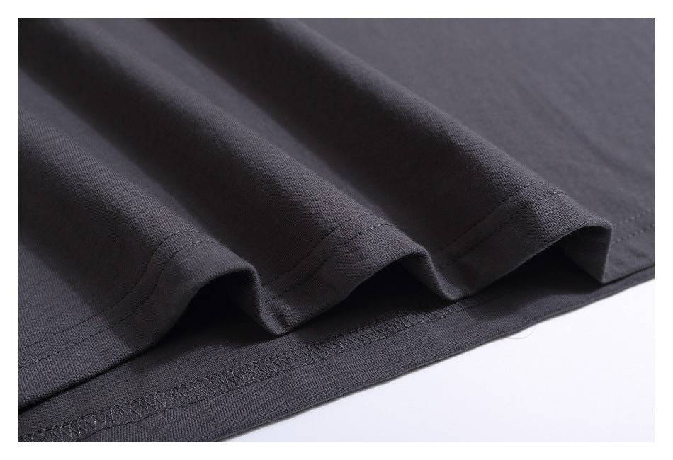 Close-up of the charcoal gray T-shirt bottom hem with folded fabric and overlock stitching.