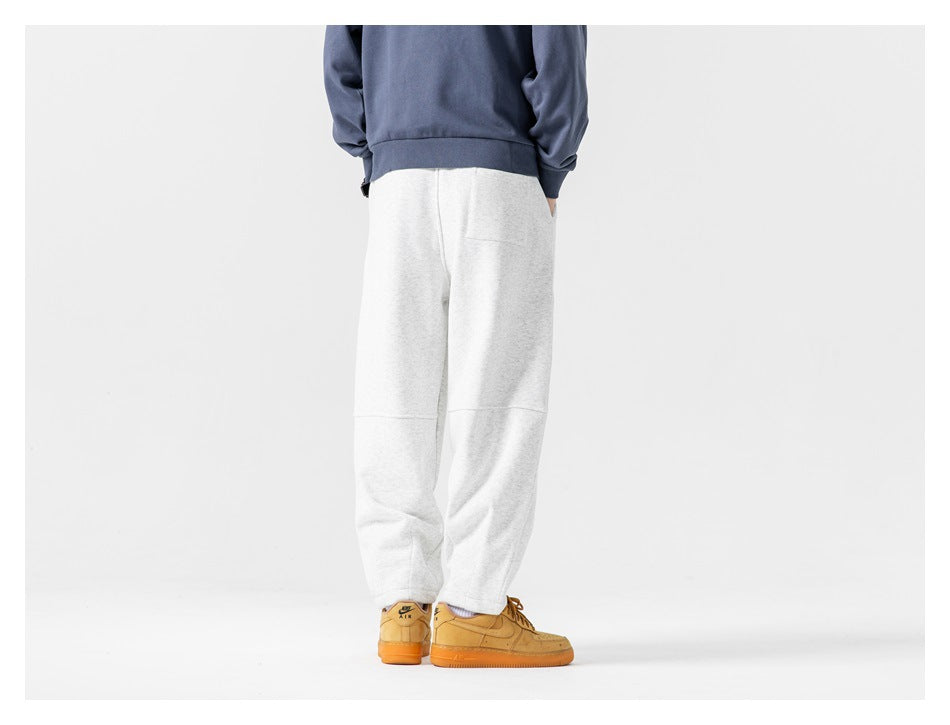 Back view of model wearing heather gray sweatpants with a seam below the knee and a back pocket