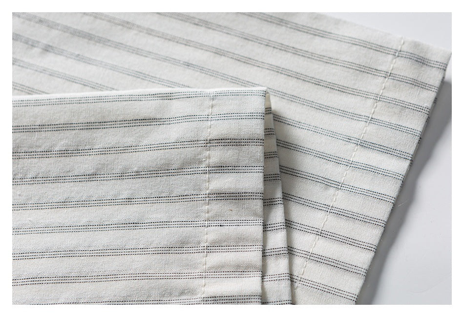 Close-up of a cream striped shirt sleeve and stitched cuff.