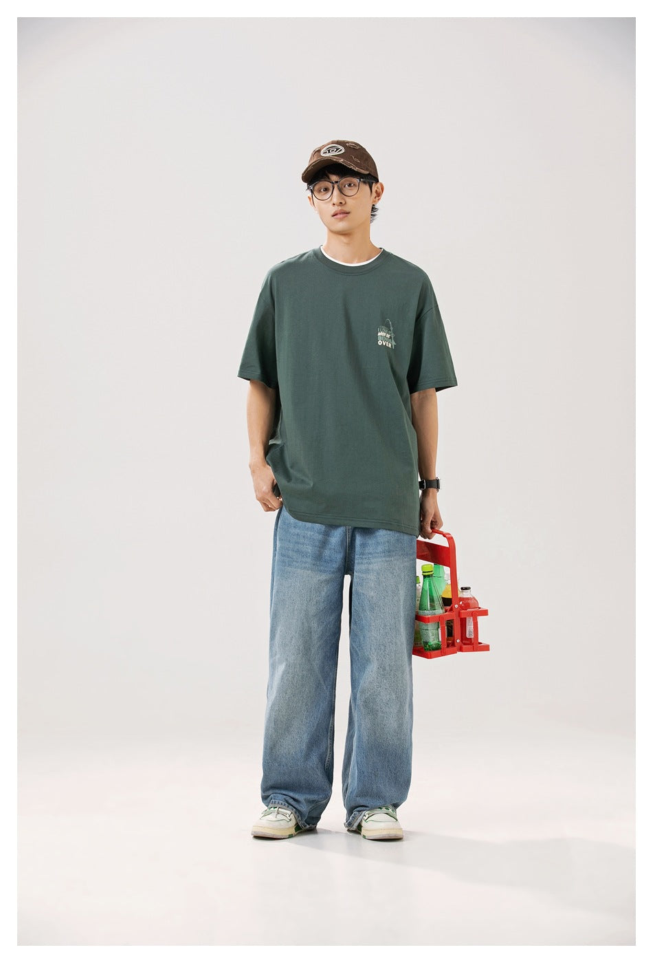 Model wearing the front of an oversized dark green T-shirt with a small chest graphic.