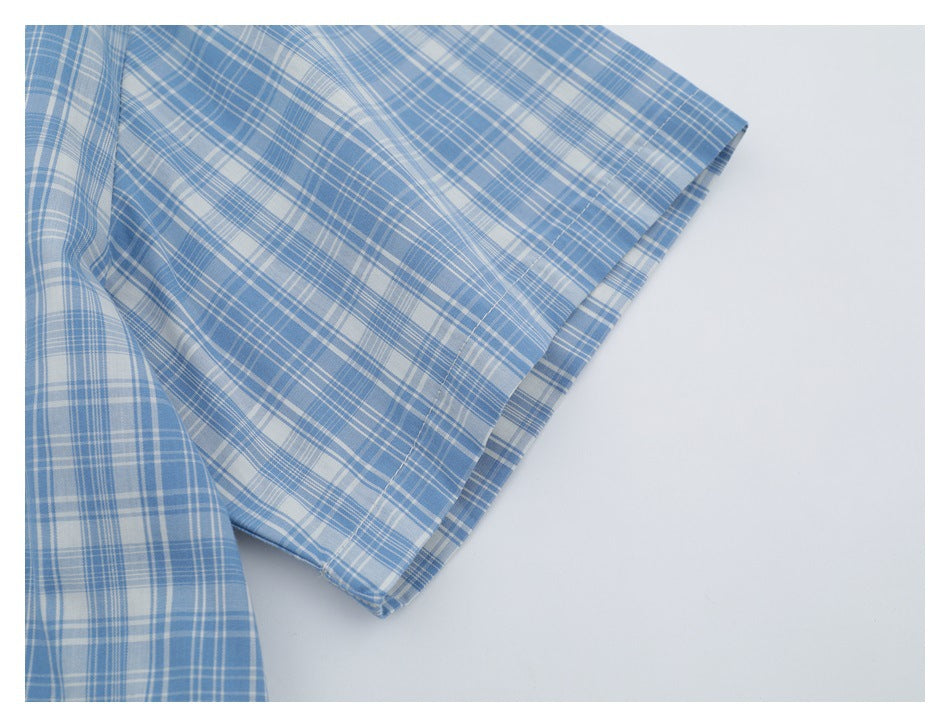 Close-up of the short sleeve and stitched hem on a blue-and-white plaid shirt.