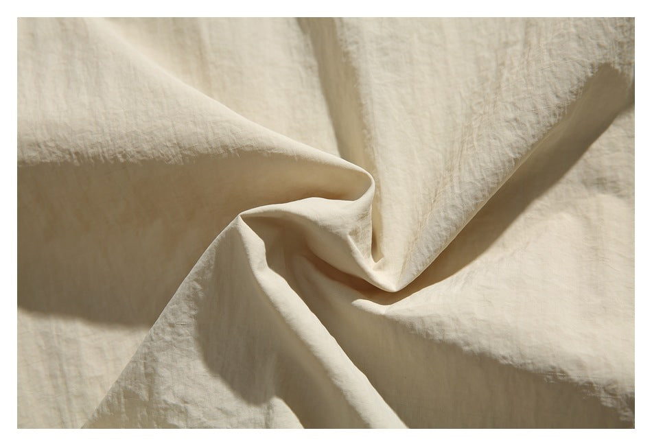 Close-up showing the softly crinkled surface and folds of ivory fabric.