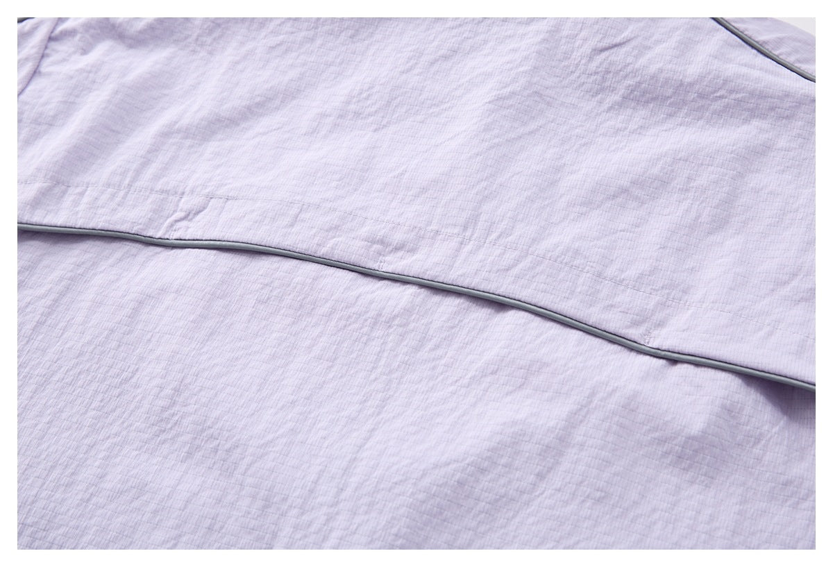Close-up of a horizontal gray-piped seam across the pale lilac top.