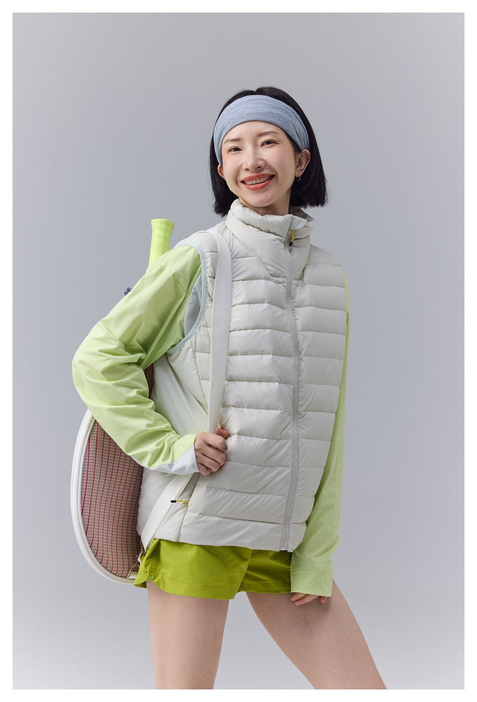 Closer front view of a woman wearing a white quilted zip vest with a high collar.