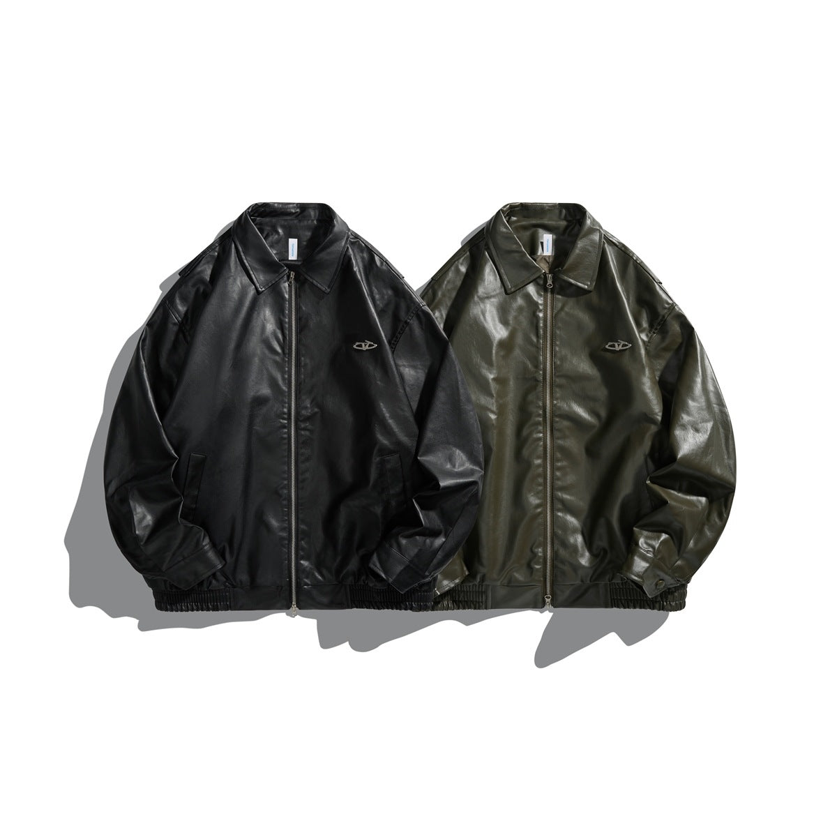 Two flat-lay zip-front jackets with pointed collars and ribbed hems, one black and one olive.