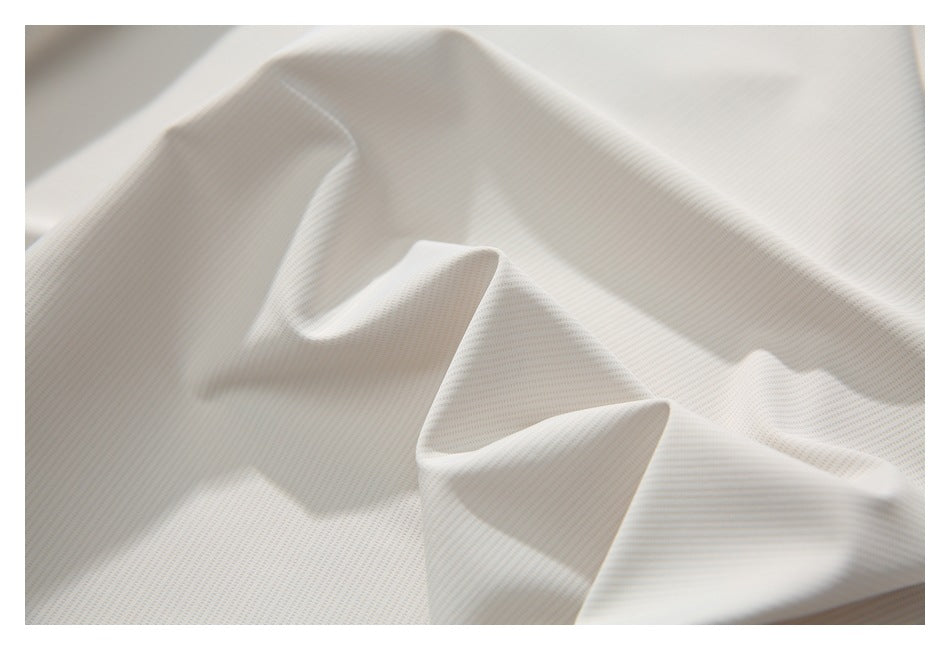 Macro view of the white shirt’s fine textured fabric folded into soft ridges.
