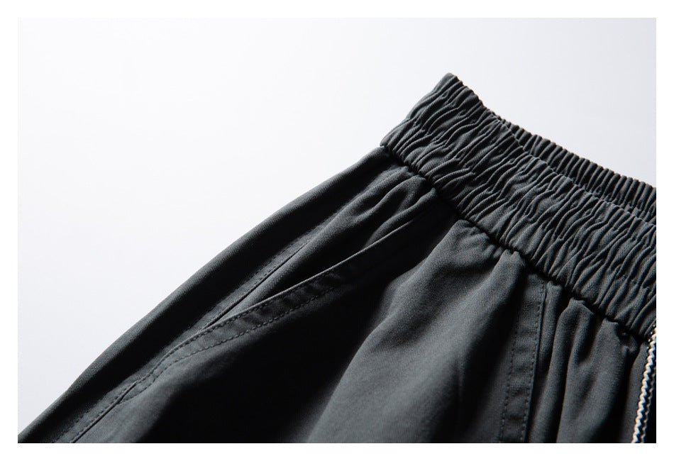 Close-up of dark charcoal pants showing a gathered elastic waistband and angled pocket seam.