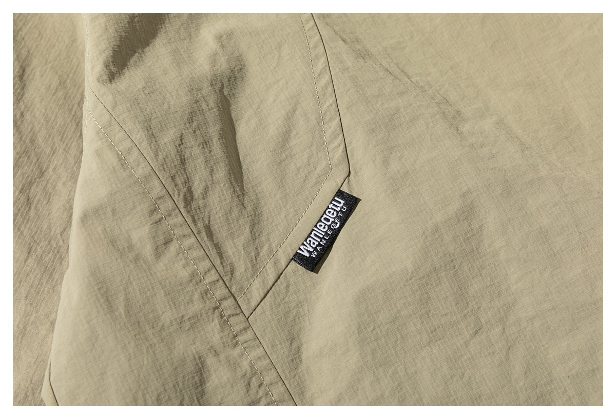 Close-up of a khaki jacket's stitched seam and small sewn brand tab.