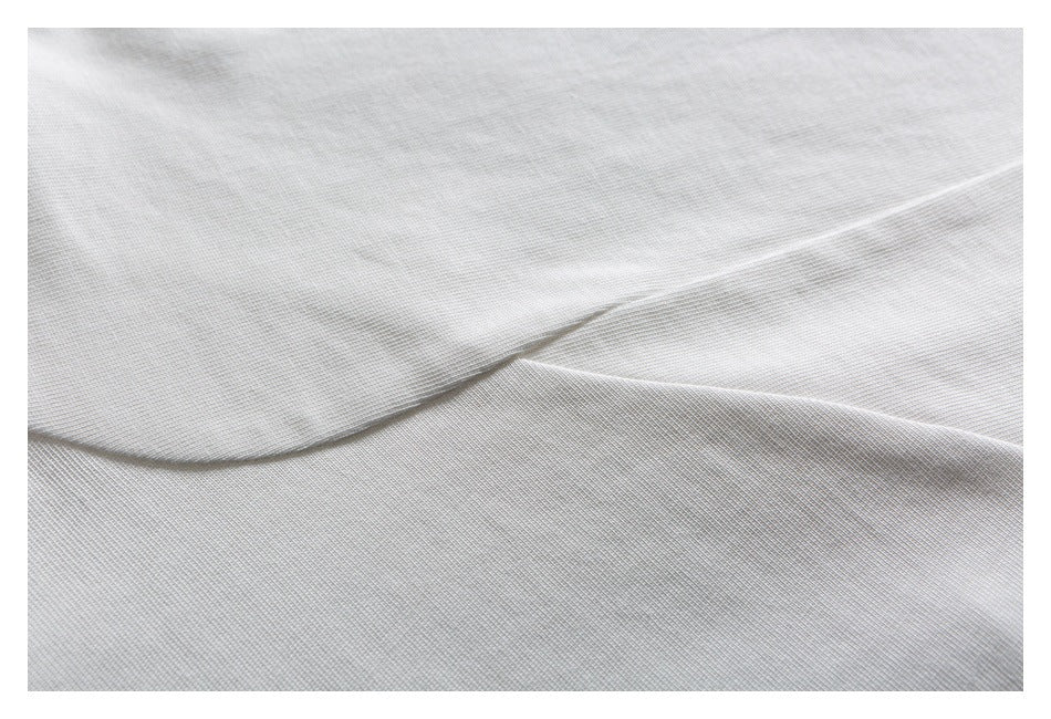Close-up of white knit fabric with a folded edge and visible fine texture.