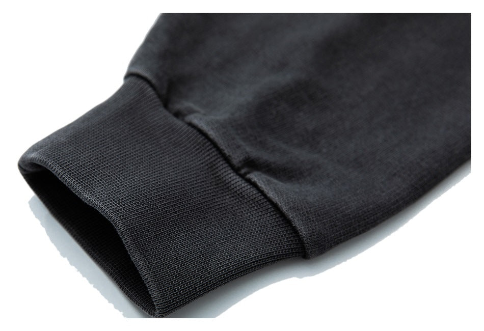 Close-up of a black hoodie sleeve with a wide ribbed cuff against a white background.