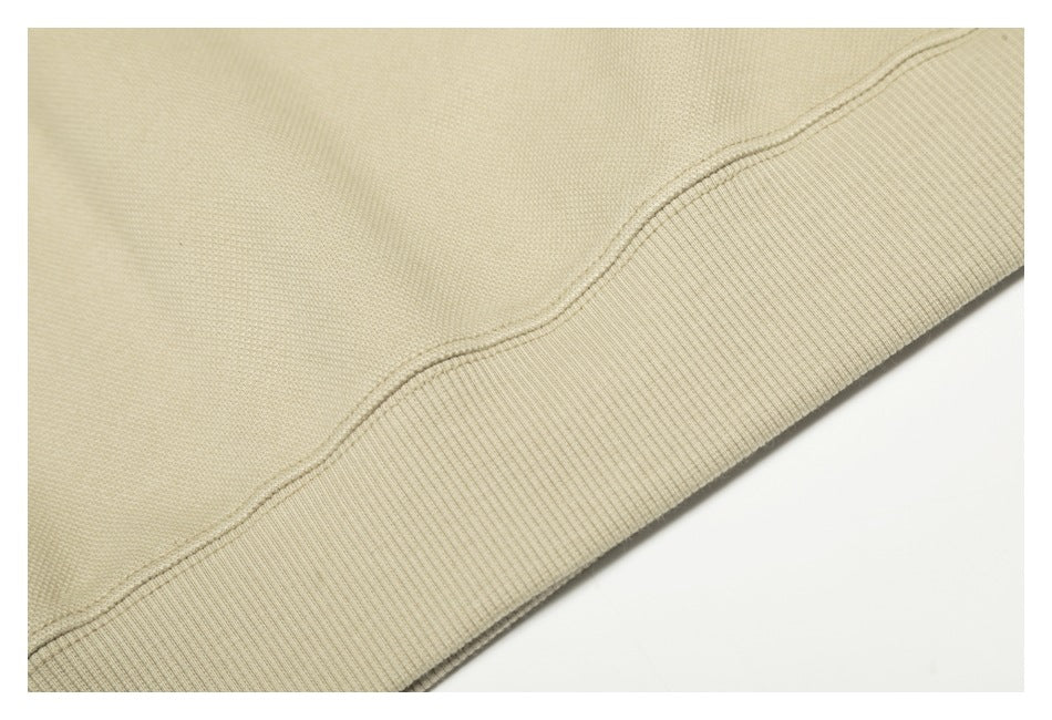 Close-up of a beige garment's ribbed hem and double-stitched seam.