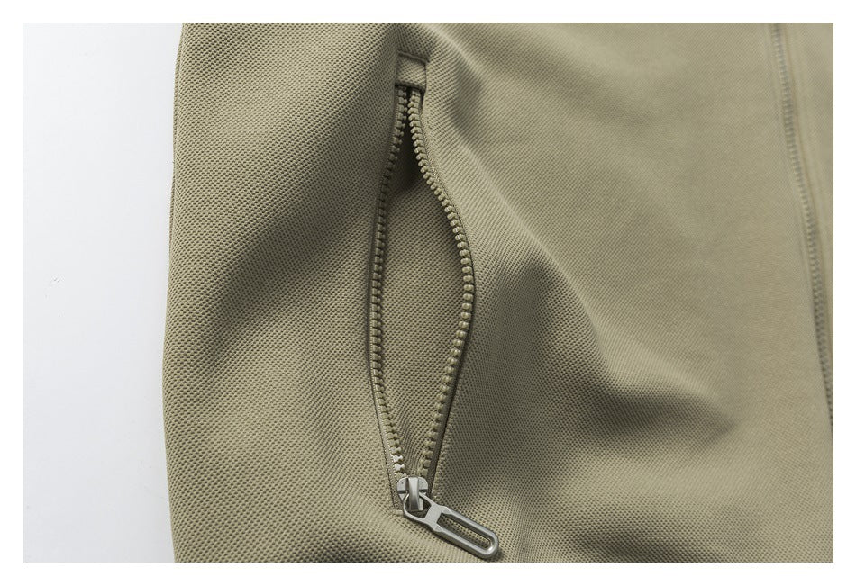 Close-up of an olive jacket's open side pocket with a chunky zipper.