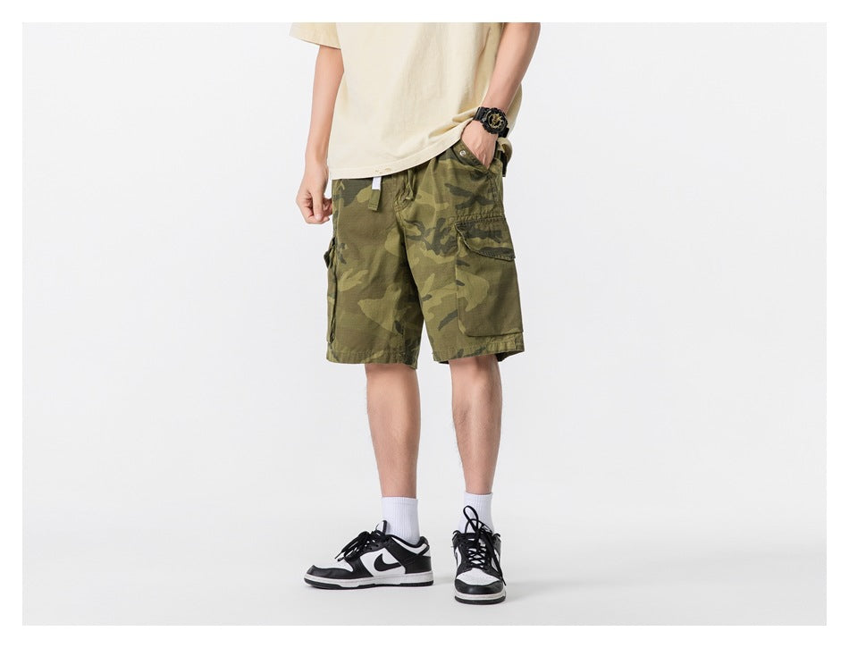 Model wearing olive camouflage cargo shorts, shown from a front three-quarter angle.