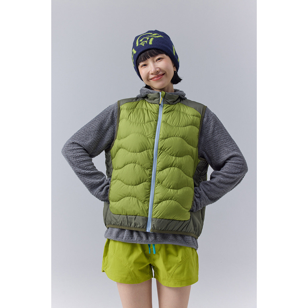 Model wearing a lime-green quilted vest with gray trim over a charcoal fleece top, shown from the front.