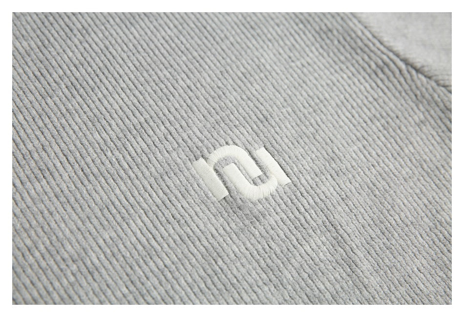 Close-up of a small white embroidered symbol on light gray ribbed knit fabric.