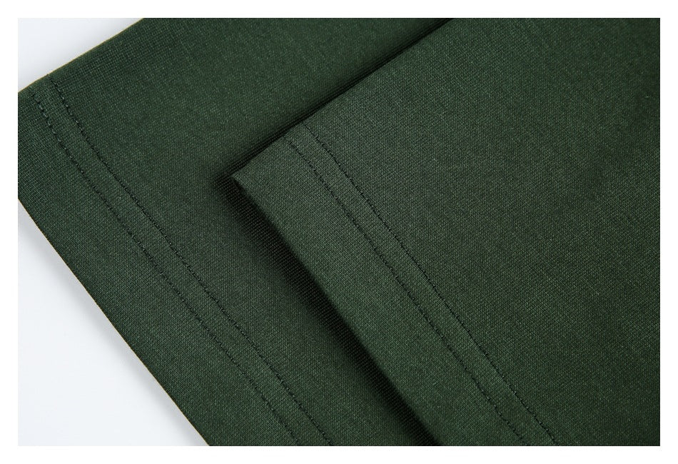 Close-up of dark green garment with overlapping panels and parallel stitched seams.
