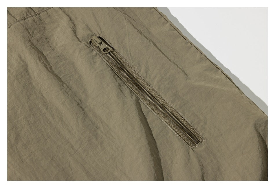 Close-up of a diagonal khaki zipper pocket on wrinkled fabric.