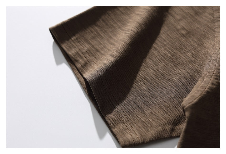 Close-up of brown shirt fabric and a stitched edge, arranged on a white background.