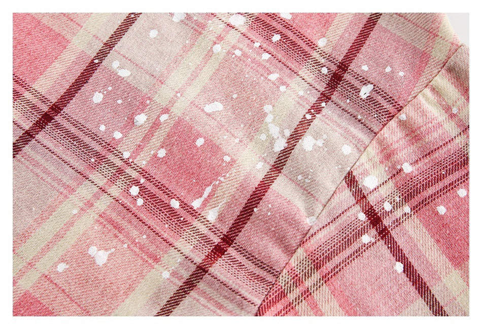 Close-up of pink, cream, and burgundy plaid fabric with white splatter marks and a seam.