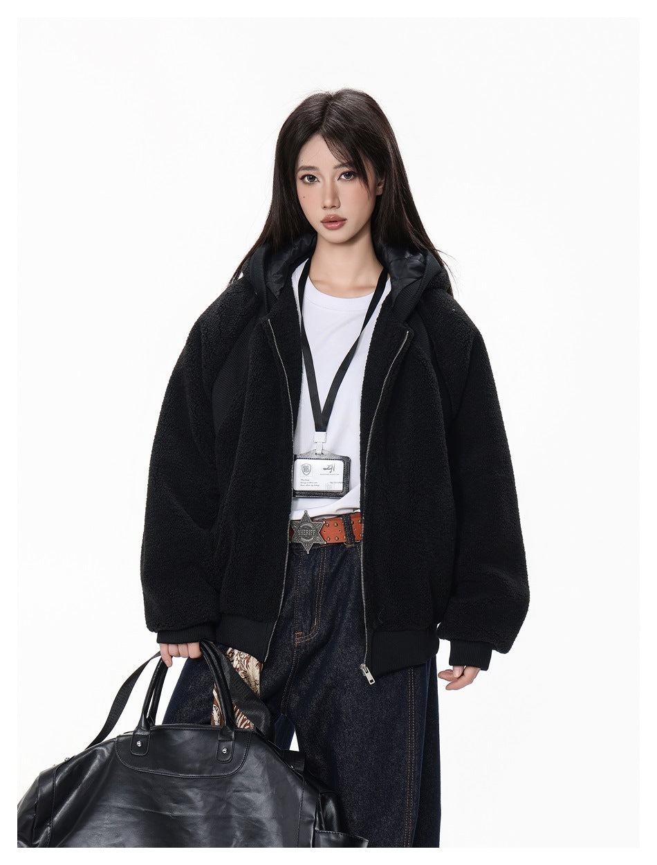 Model wearing an open black hooded jacket over a white shirt, with dark jeans and a shoulder bag.