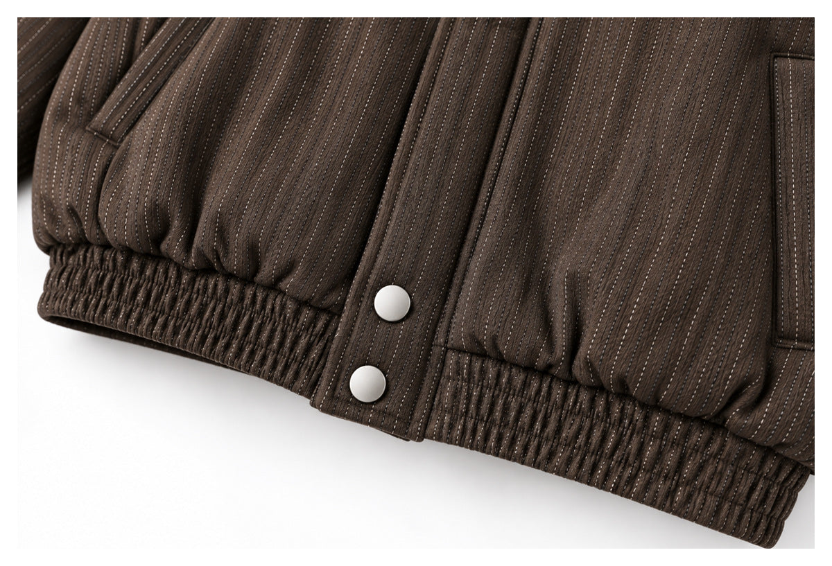 Close-up of a dark brown pinstriped garment hem with elastic gathering, silver snaps, and a welt pocket edge.