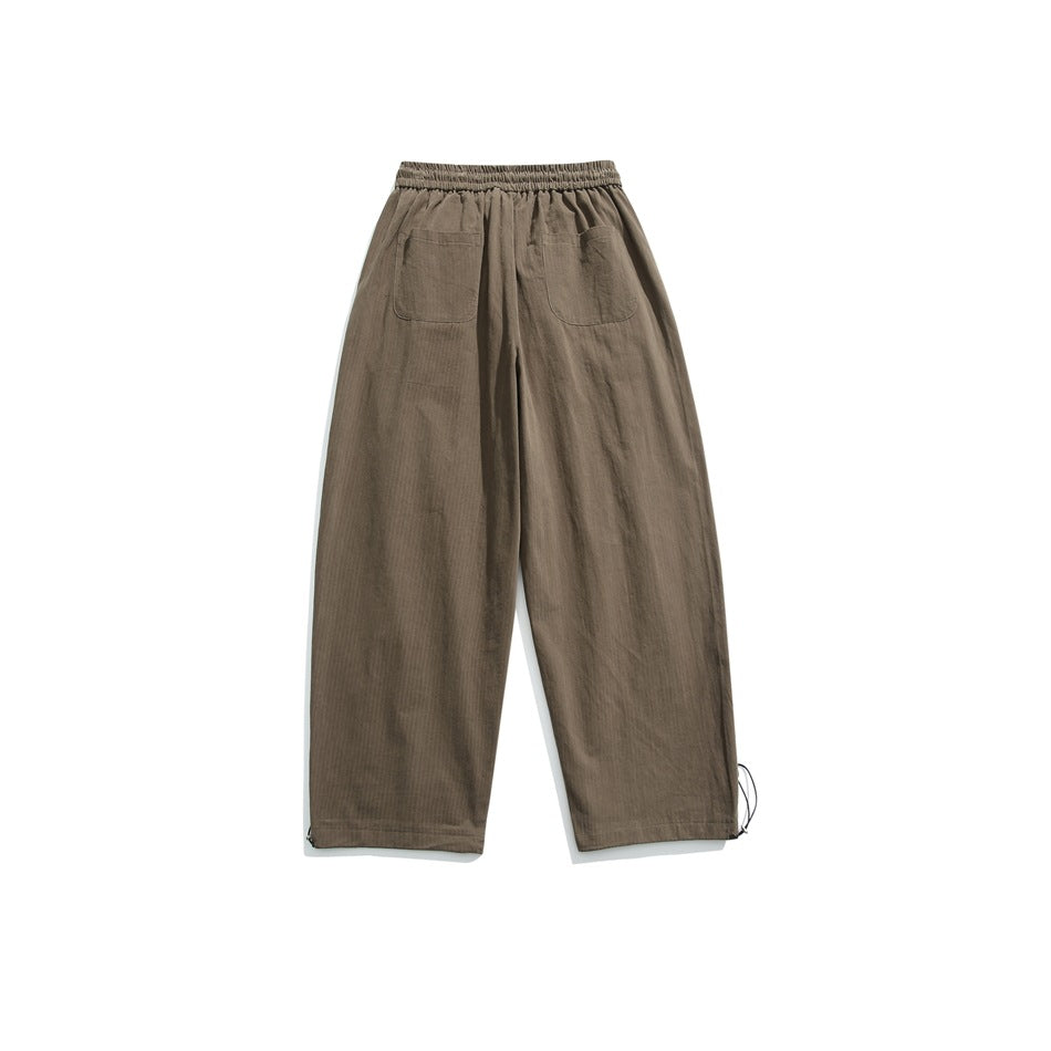 Back view of taupe wide-leg trousers with an elastic waist, two patch pockets, and adjustable ankle cords.