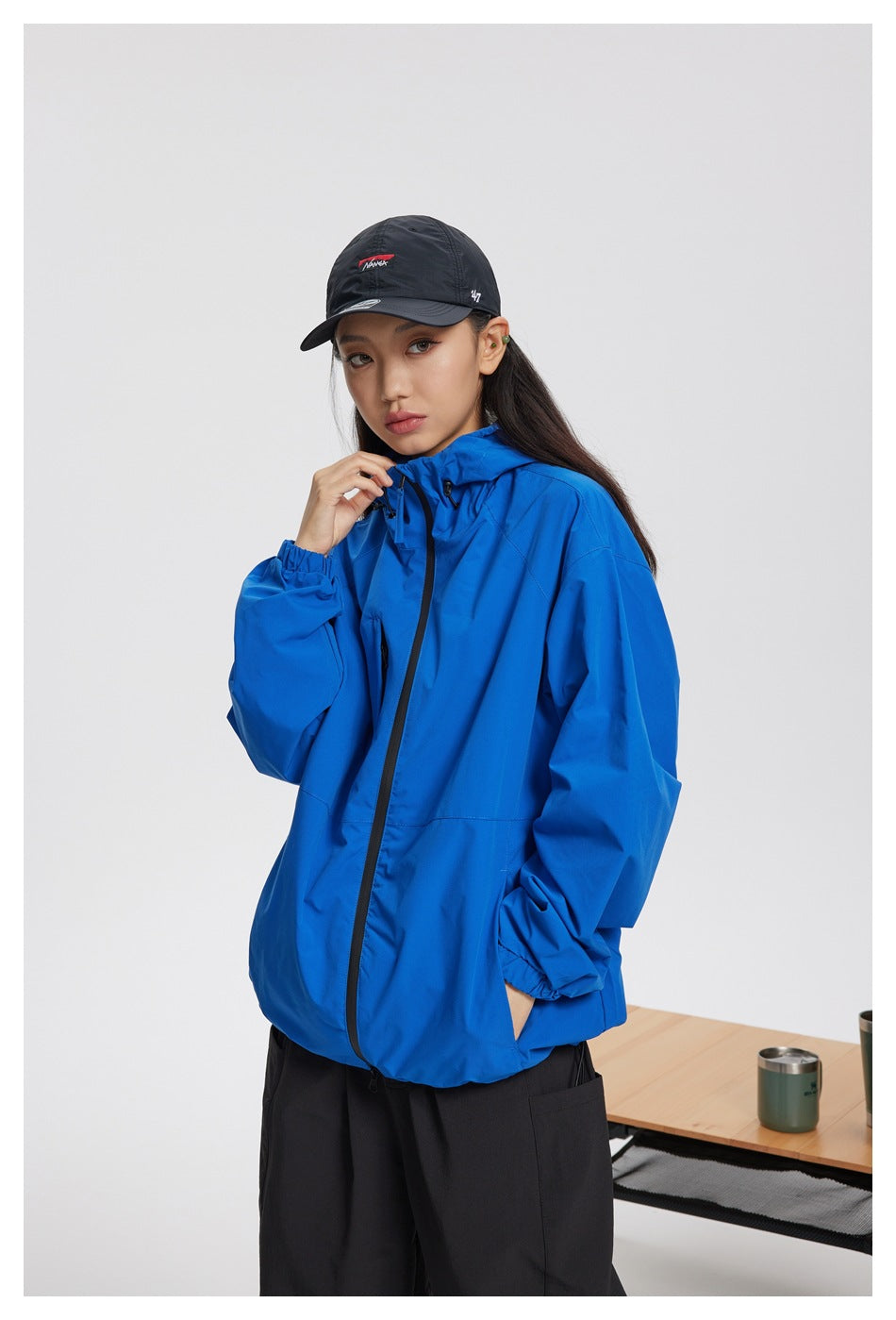 Closer view of a person wearing a bright blue hooded jacket with a black cap.