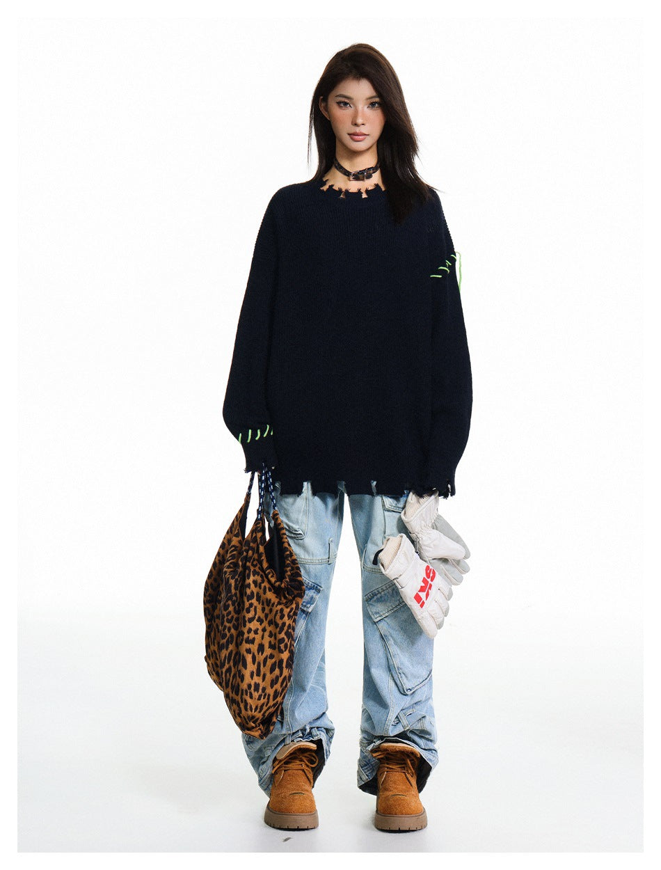 Full-length model wearing a dark navy oversized sweater with a distressed neckline and hem and bright green stitching.