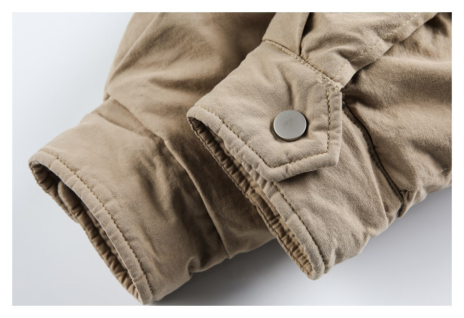 Close-up of a beige sleeve cuff with a round snap tab and stitched edge.