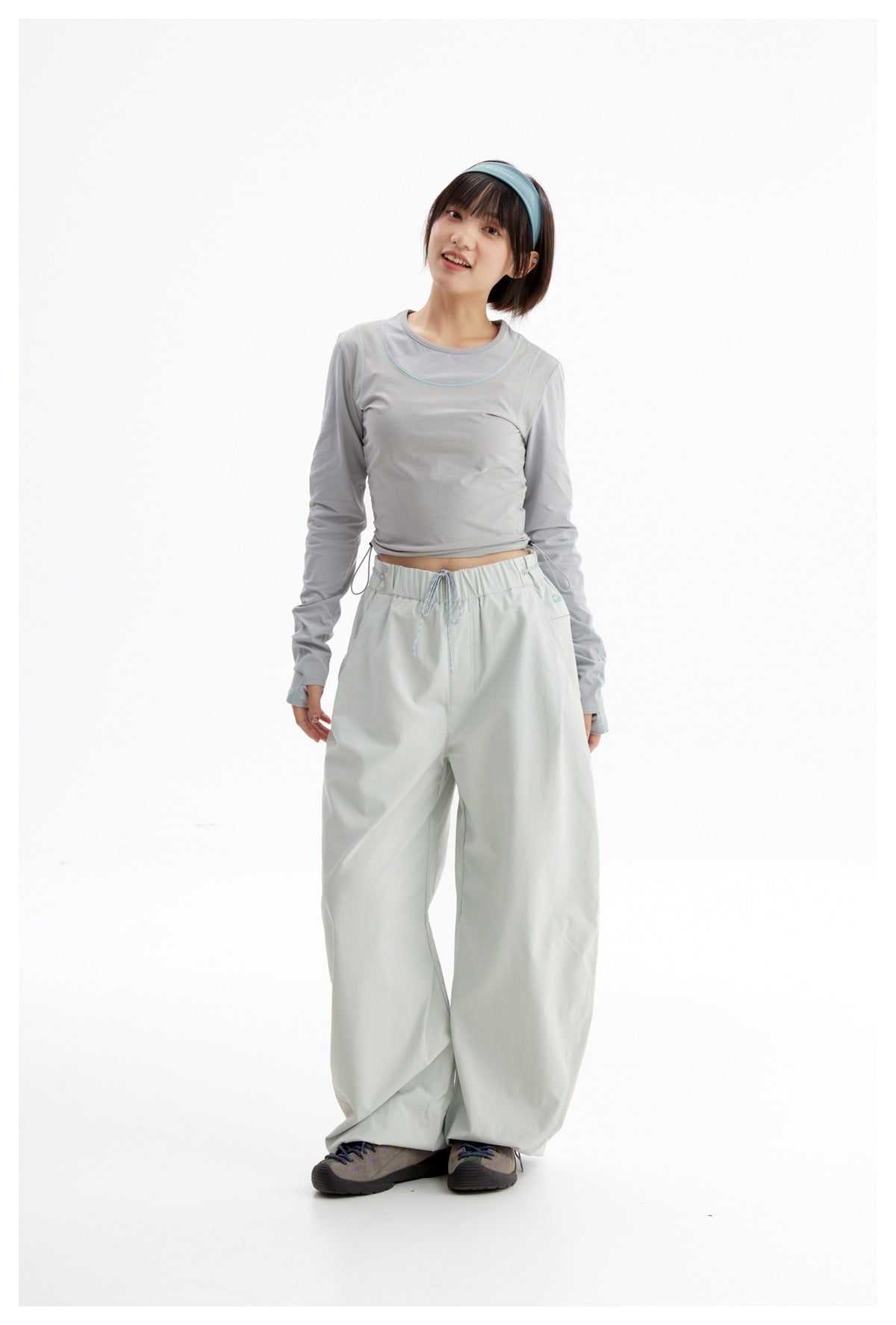 Model wearing a light gray long-sleeve top with teal piping and pale mint wide-leg pants; the top sits above the waistband.