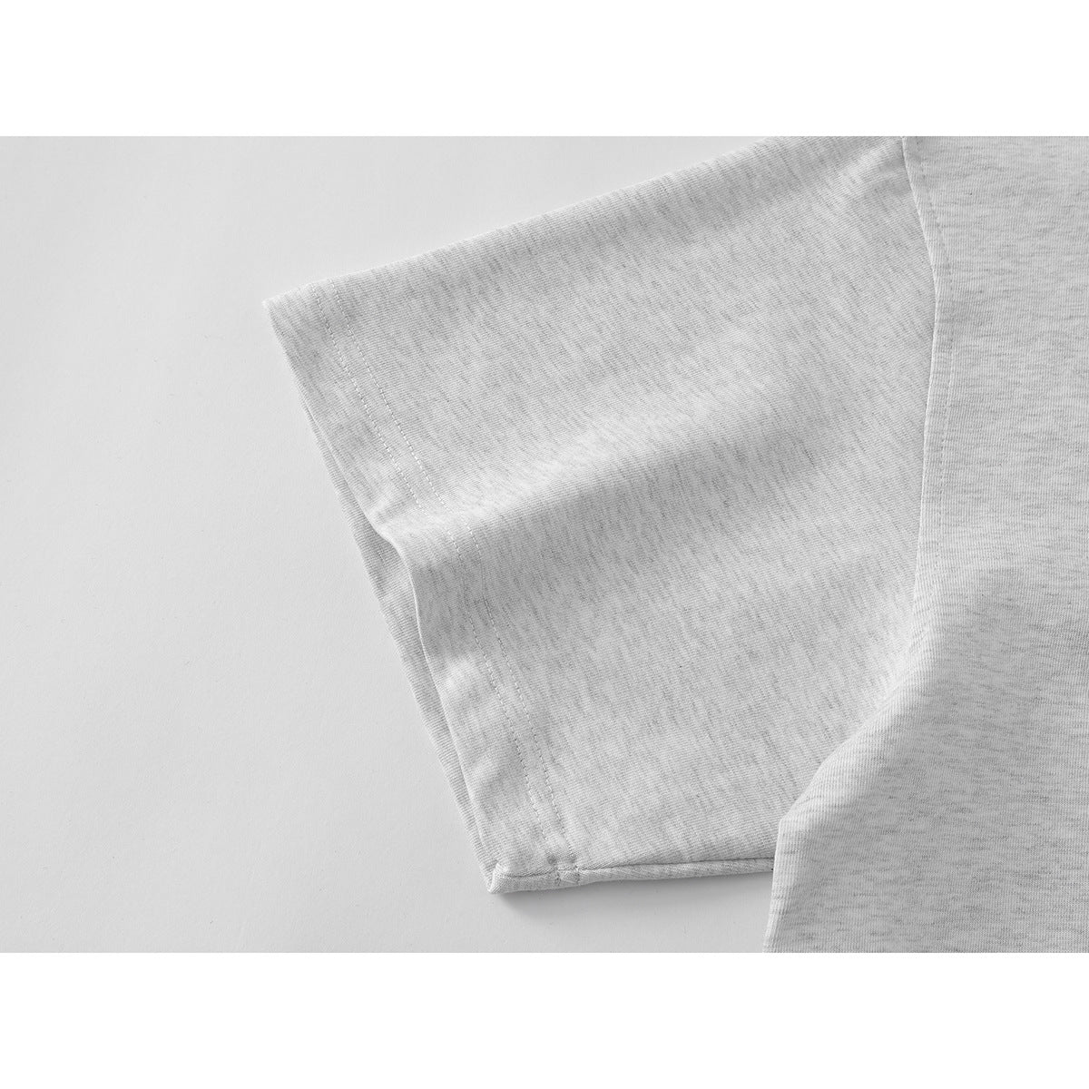 Close-up of the short sleeve and stitched hem of a light gray polo shirt.
